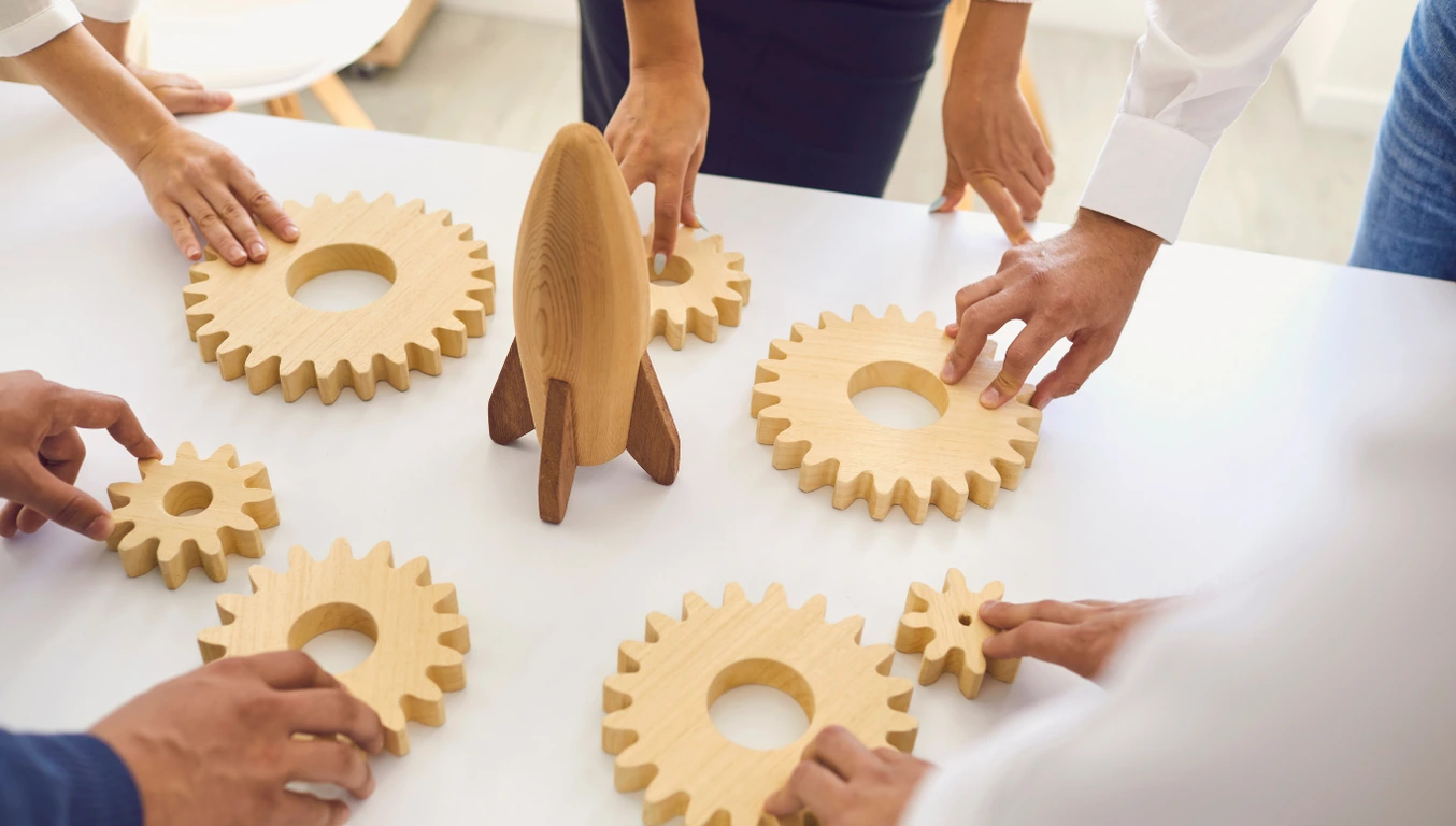 people assembling a wooden toy rocket with gears